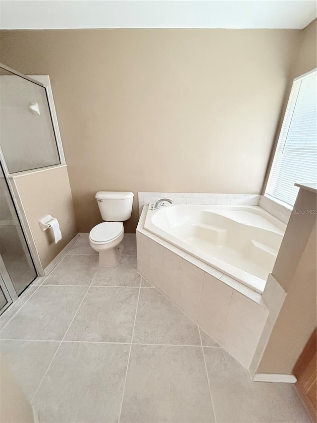 bathroom featuring tile patterned flooring, a relaxing tiled tub, and toilet