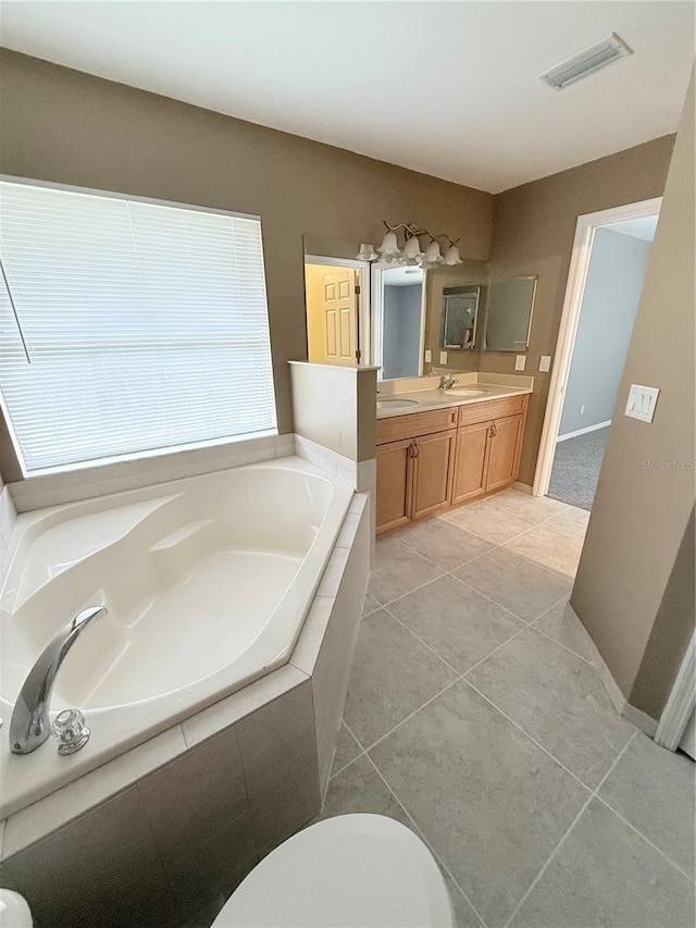 bathroom with tile patterned flooring, vanity, and tiled bath