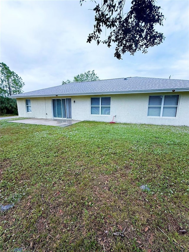 back of property with a yard and a patio area