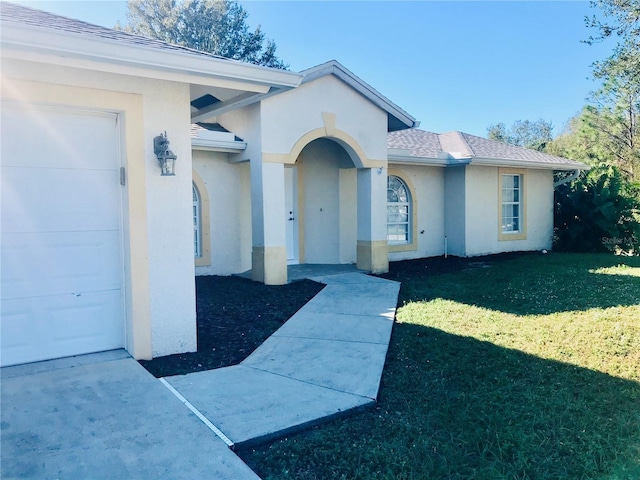 view of exterior entry with a lawn and a garage