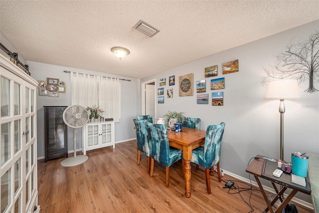 dining room featuring a textured ceiling, hardwood / wood-style flooring, and a barn door