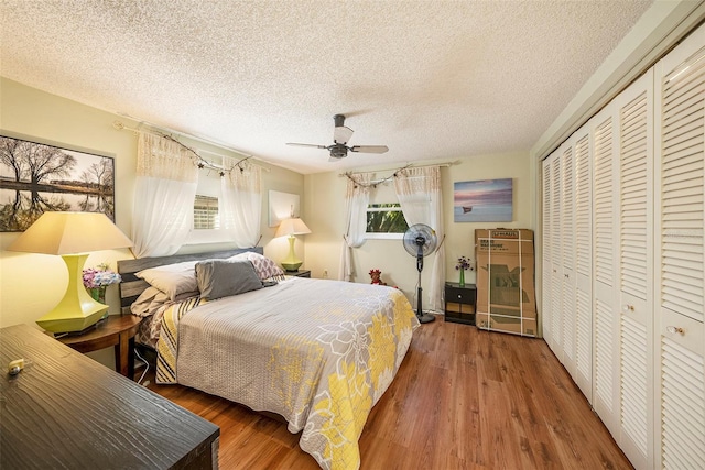 bedroom with a textured ceiling, ceiling fan, dark wood-type flooring, and a closet