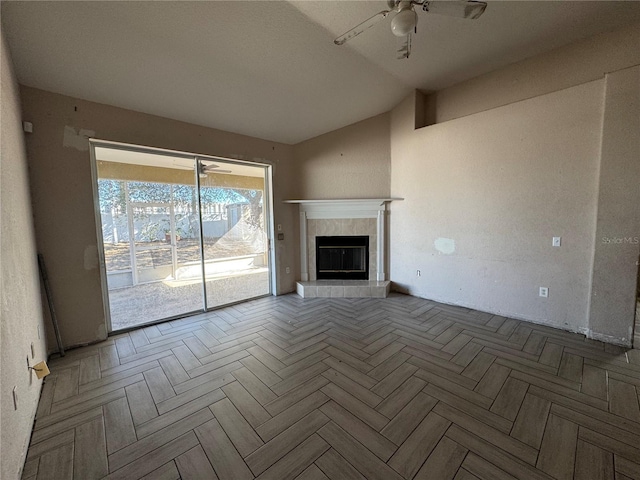 unfurnished living room featuring a tile fireplace, ceiling fan, and lofted ceiling