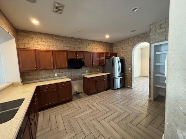 kitchen featuring stainless steel fridge, sink, and light parquet flooring