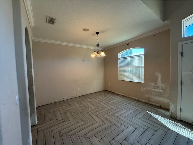 empty room with a textured ceiling, an inviting chandelier, light parquet floors, and ornamental molding