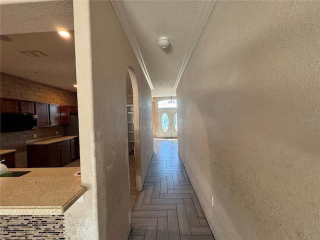 hall with ornamental molding, a textured ceiling, and light parquet flooring