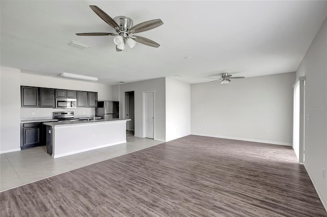 kitchen featuring appliances with stainless steel finishes, a center island with sink, light hardwood / wood-style flooring, and ceiling fan