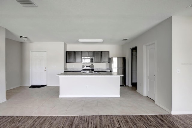 kitchen featuring sink, light wood-type flooring, stainless steel appliances, and an island with sink