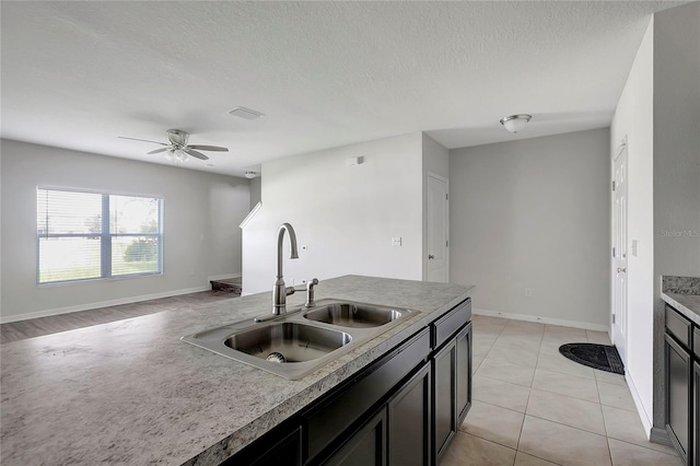 kitchen featuring a textured ceiling, ceiling fan, light tile patterned flooring, and sink