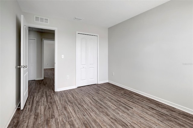 unfurnished bedroom with a closet and dark wood-type flooring