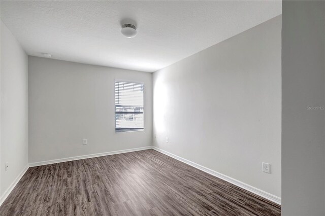 empty room featuring dark hardwood / wood-style flooring and a textured ceiling