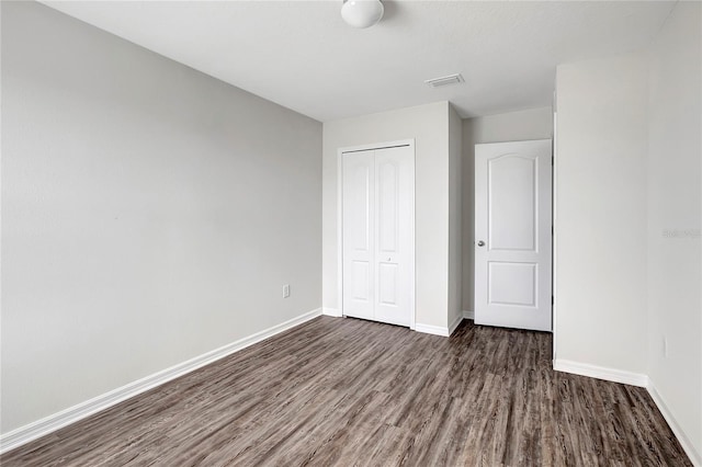 unfurnished bedroom with dark hardwood / wood-style flooring and a closet