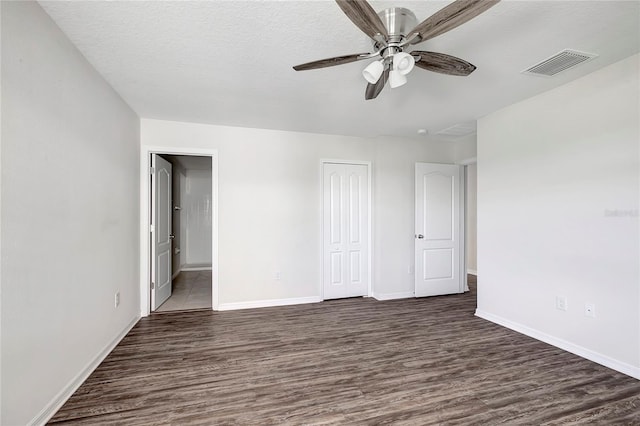 unfurnished bedroom with a closet, ceiling fan, dark hardwood / wood-style flooring, and a textured ceiling