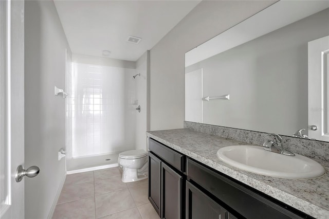 bathroom with tile patterned floors, vanity, toilet, and a tile shower