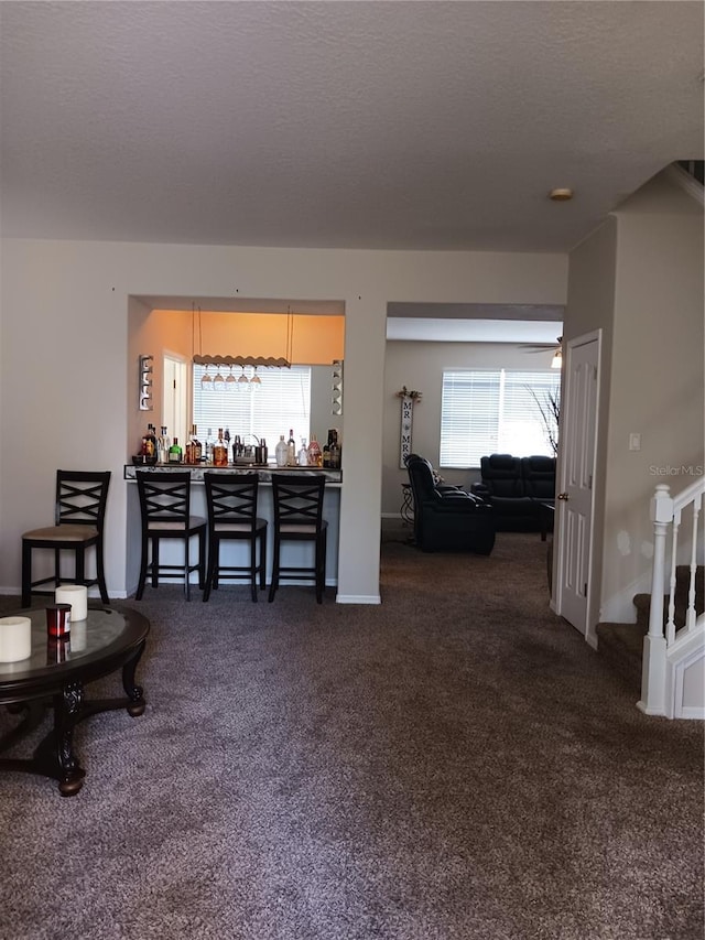 carpeted living room with a textured ceiling and indoor bar