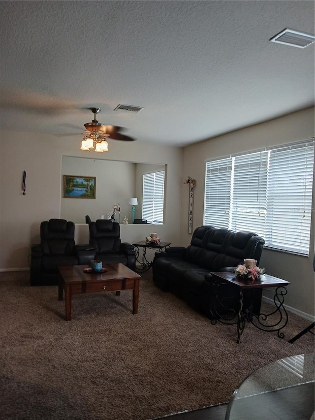 carpeted living room with ceiling fan and a textured ceiling