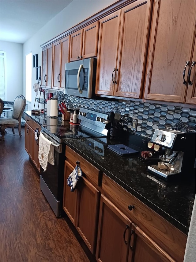 kitchen with decorative backsplash, dark hardwood / wood-style flooring, stainless steel appliances, and dark stone countertops