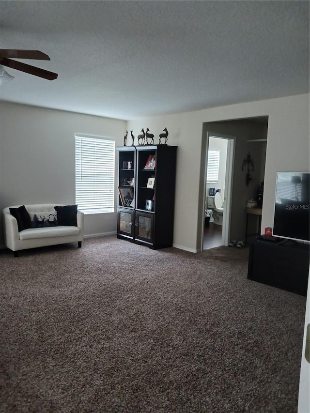 living room featuring ceiling fan, a textured ceiling, and carpet flooring