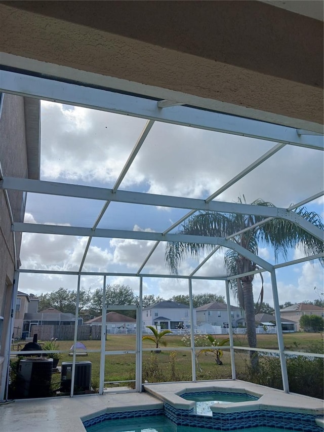 view of pool with an in ground hot tub, glass enclosure, a lawn, and a patio