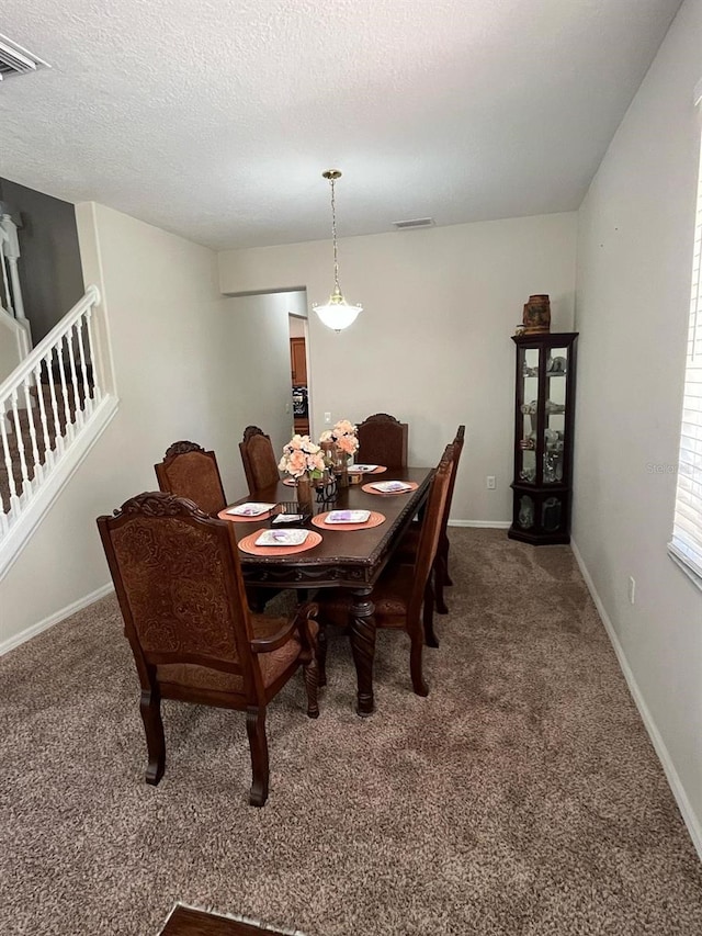 carpeted dining room with baseboards, a textured ceiling, and stairway