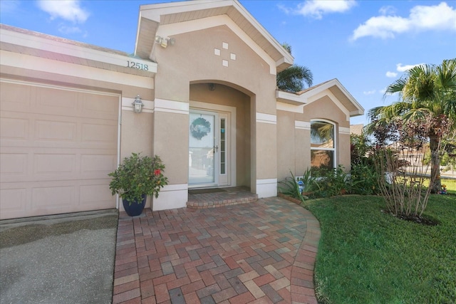 view of exterior entry with a yard and a garage