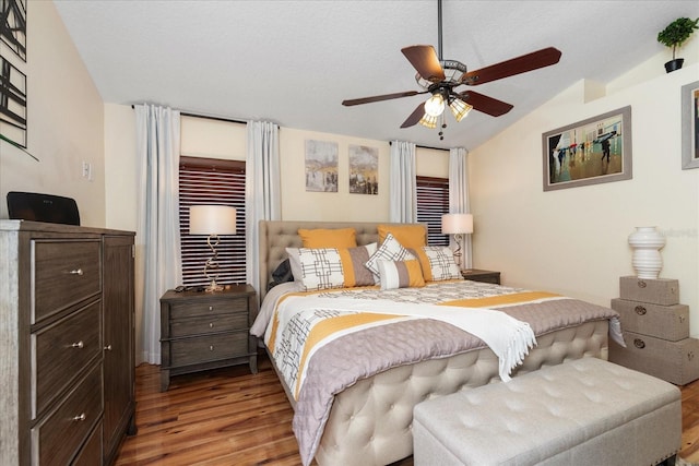 bedroom with ceiling fan, lofted ceiling, hardwood / wood-style floors, and a textured ceiling