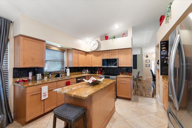 kitchen with appliances with stainless steel finishes, a breakfast bar, sink, a center island, and light tile patterned floors