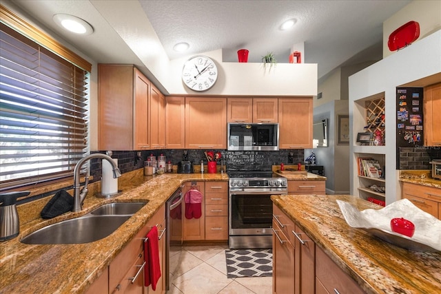 kitchen with light stone counters, sink, light tile patterned floors, and stainless steel appliances