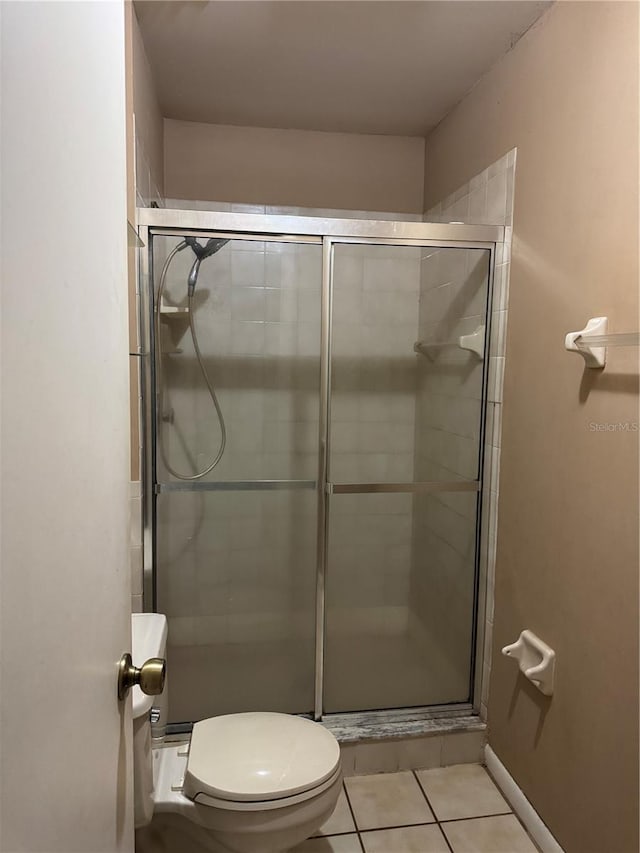 bathroom with tile patterned floors, a shower with shower door, and toilet