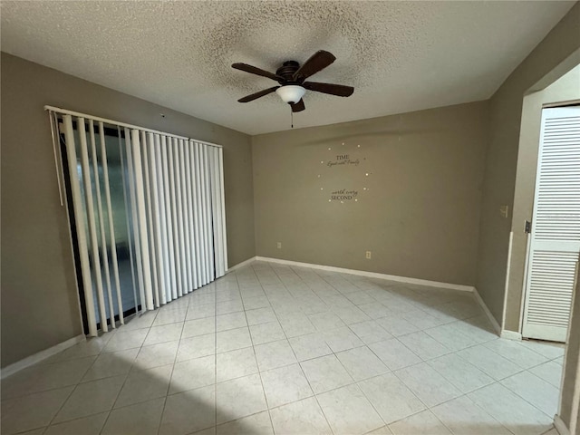 spare room featuring ceiling fan, light tile patterned floors, and a textured ceiling