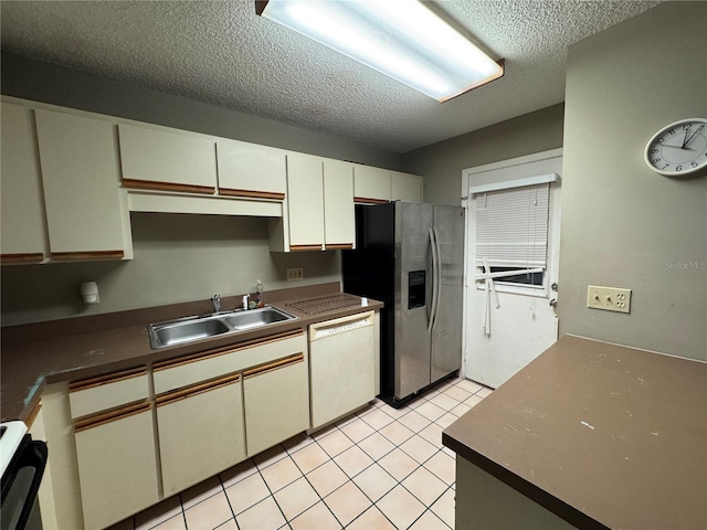 kitchen featuring dishwasher, sink, stainless steel fridge, stove, and a textured ceiling