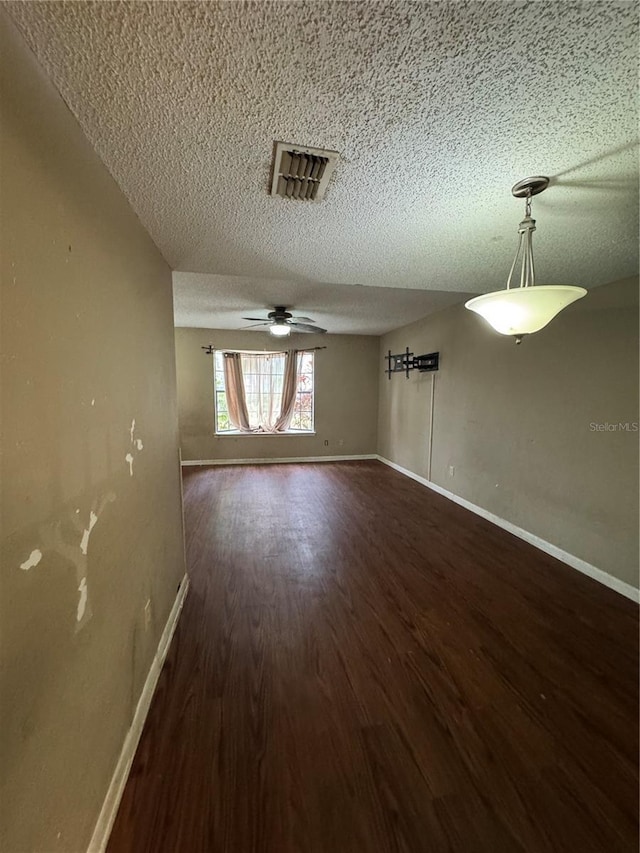 empty room with ceiling fan, dark hardwood / wood-style flooring, and a textured ceiling