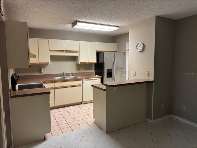 kitchen featuring cream cabinetry, dishwasher, stainless steel fridge, and sink