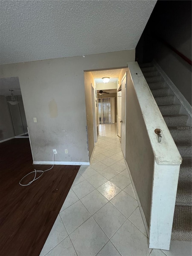 hall featuring light tile patterned floors and a textured ceiling