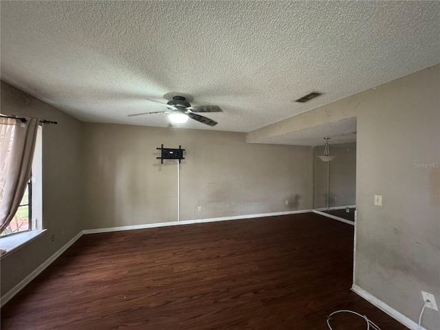 unfurnished room featuring ceiling fan, dark wood-type flooring, and a textured ceiling