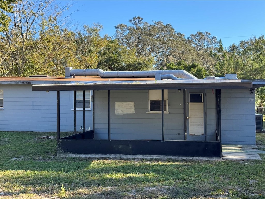 rear view of property featuring a yard and central AC