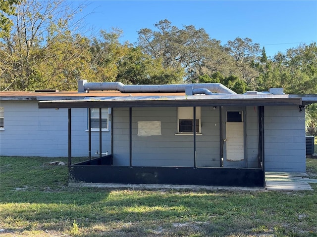 rear view of property with cooling unit and a yard