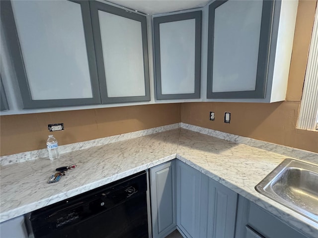 kitchen with gray cabinets, black dishwasher, sink, and light stone counters