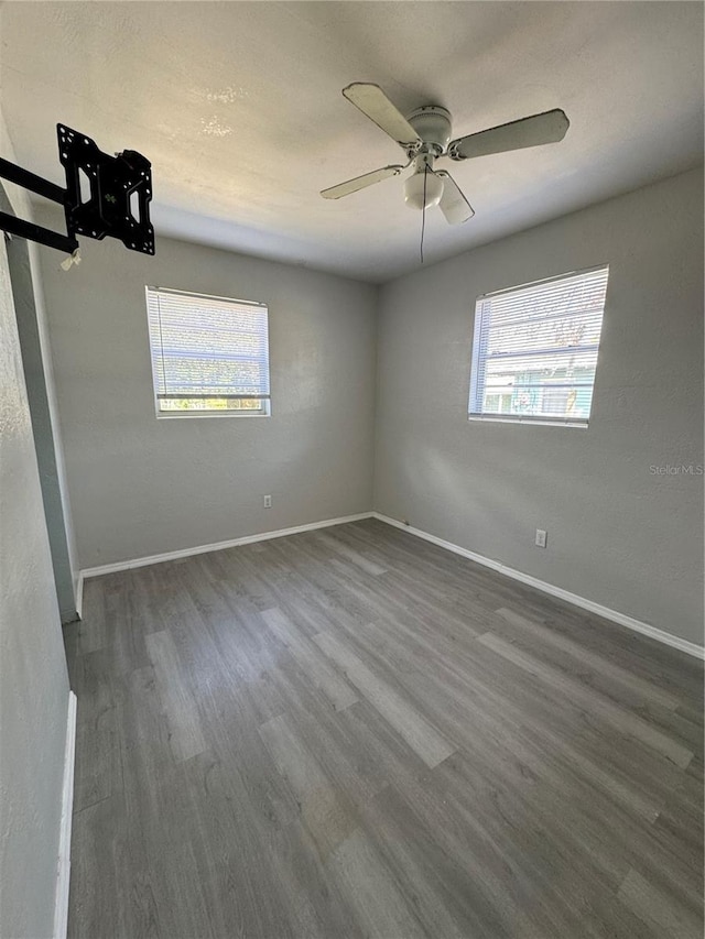 spare room featuring dark wood-type flooring, ceiling fan, and plenty of natural light