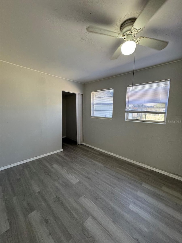 unfurnished room featuring ceiling fan, dark hardwood / wood-style floors, a textured ceiling, and a wealth of natural light