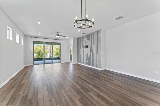 empty room with ceiling fan with notable chandelier and dark hardwood / wood-style floors