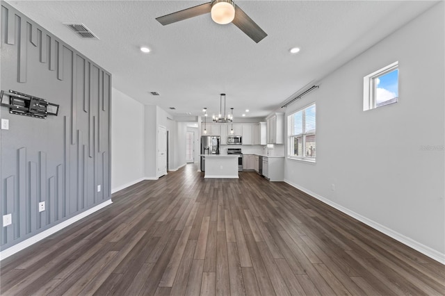 unfurnished living room featuring a textured ceiling, dark hardwood / wood-style flooring, and ceiling fan with notable chandelier