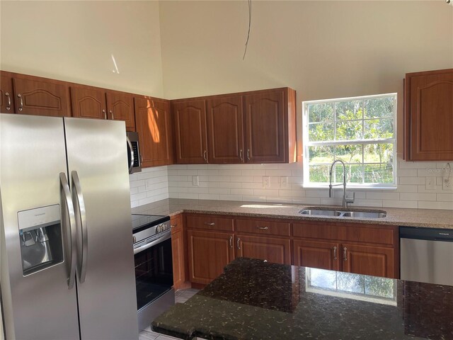 kitchen featuring dark stone countertops, decorative backsplash, sink, and stainless steel appliances