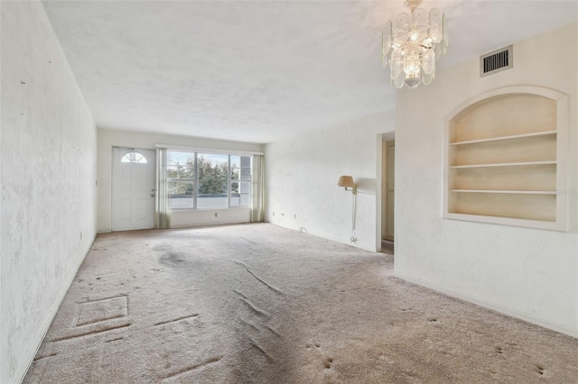 unfurnished living room featuring built in shelves, carpet, and a notable chandelier