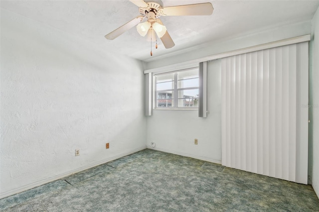 unfurnished room with ceiling fan and dark colored carpet