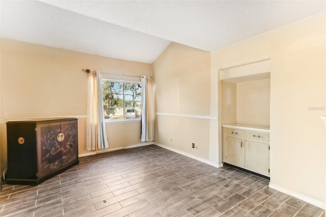 spare room with a textured ceiling, lofted ceiling, and hardwood / wood-style flooring