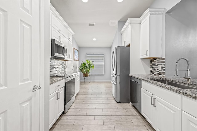 kitchen with appliances with stainless steel finishes, stone countertops, white cabinetry, and sink