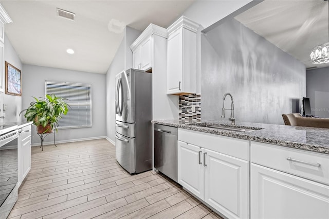 kitchen featuring sink, appliances with stainless steel finishes, light hardwood / wood-style floors, light stone counters, and white cabinetry