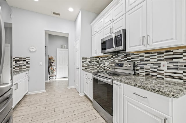 kitchen with stone counters, white cabinets, light hardwood / wood-style flooring, tasteful backsplash, and stainless steel appliances