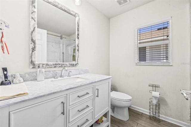 bathroom with wood-type flooring, vanity, toilet, and a shower with shower door